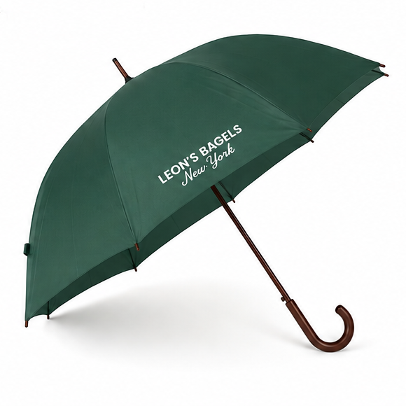 A dark green umbrella with 'LEON'S BAGELS New York' printed in white on the canopy, featuring a brown wooden-style curved handle and dark brown shaft, shown on a white background.