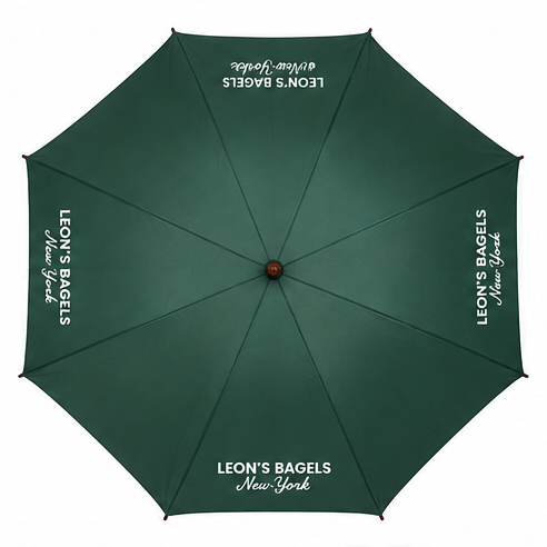 A dark green umbrella shown from a top-down view, featuring white printed text that reads 'LEON'S BAGELS New York' on multiple panels.